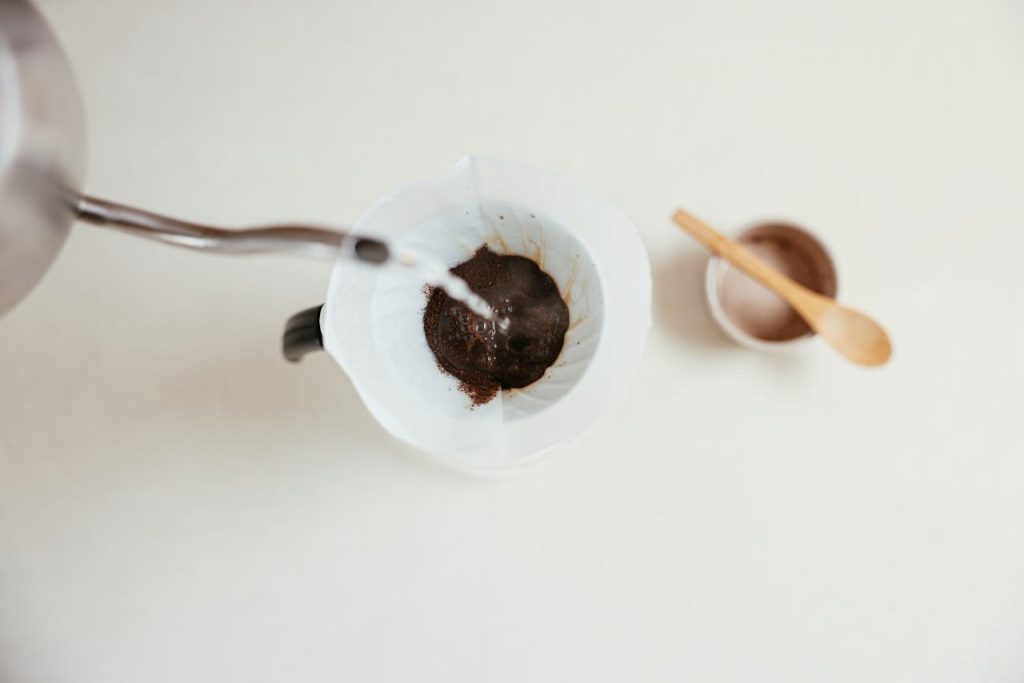 A close-up shot of pour over coffee brewing with a gooseneck kettle and filter.