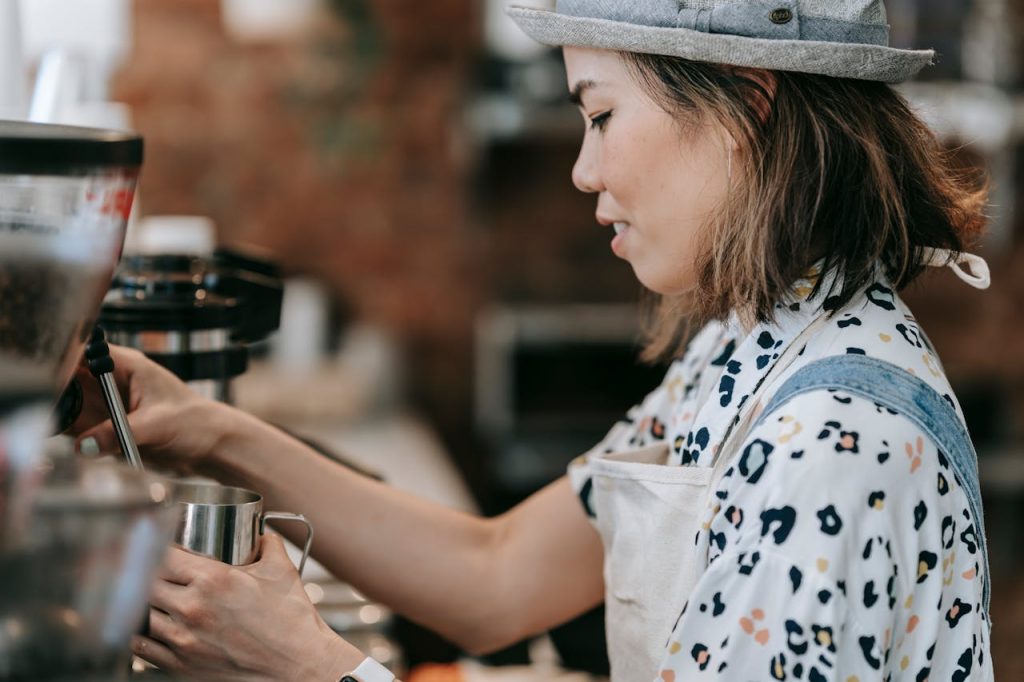 Asian woman barista making coffee in a cozy cafe using an espresso machine.
